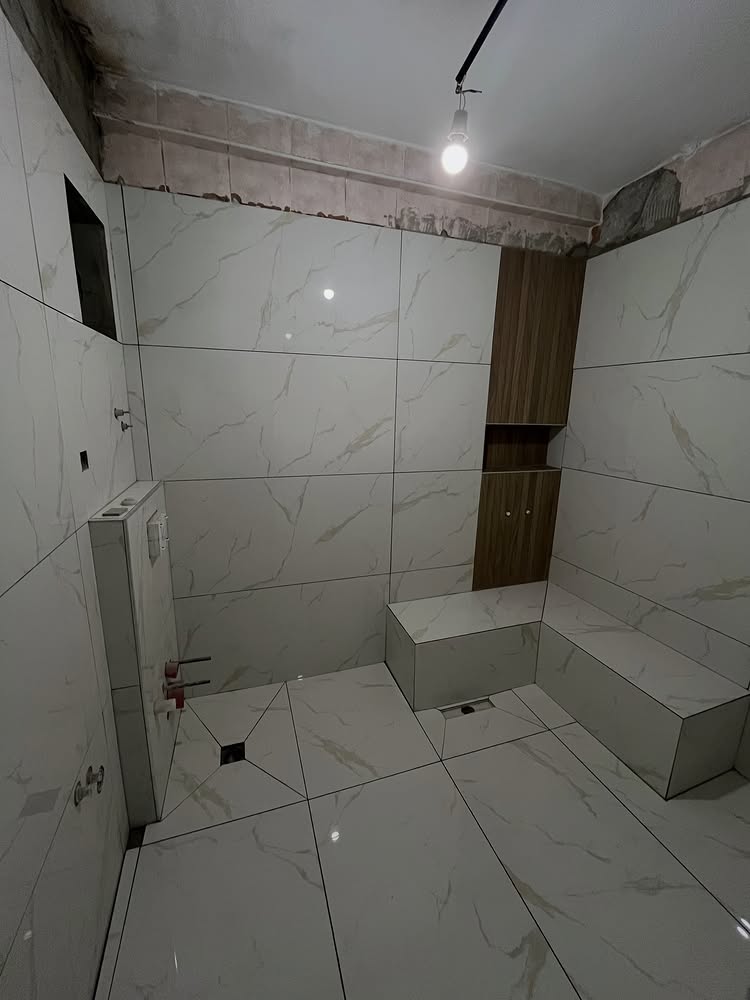 Mersin büyük ebat banyo seramik döşeme: Calacatta mermer desenli duvar, gömme bank ve linear süzgeç kesimi